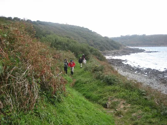 Walkers following a coastal path above the sea