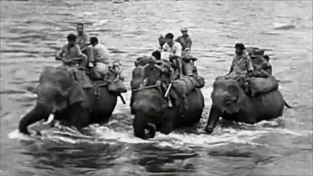 People crossing a river on three elephants in Burma