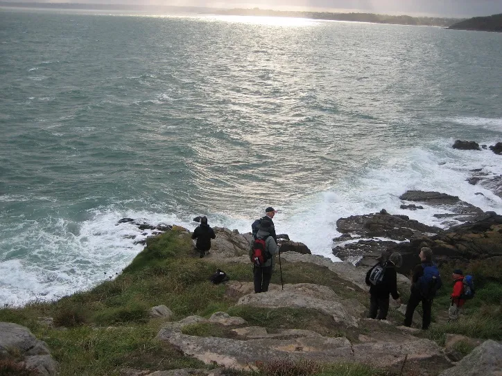Walkers descending a rocky section of the Brittany coastal path